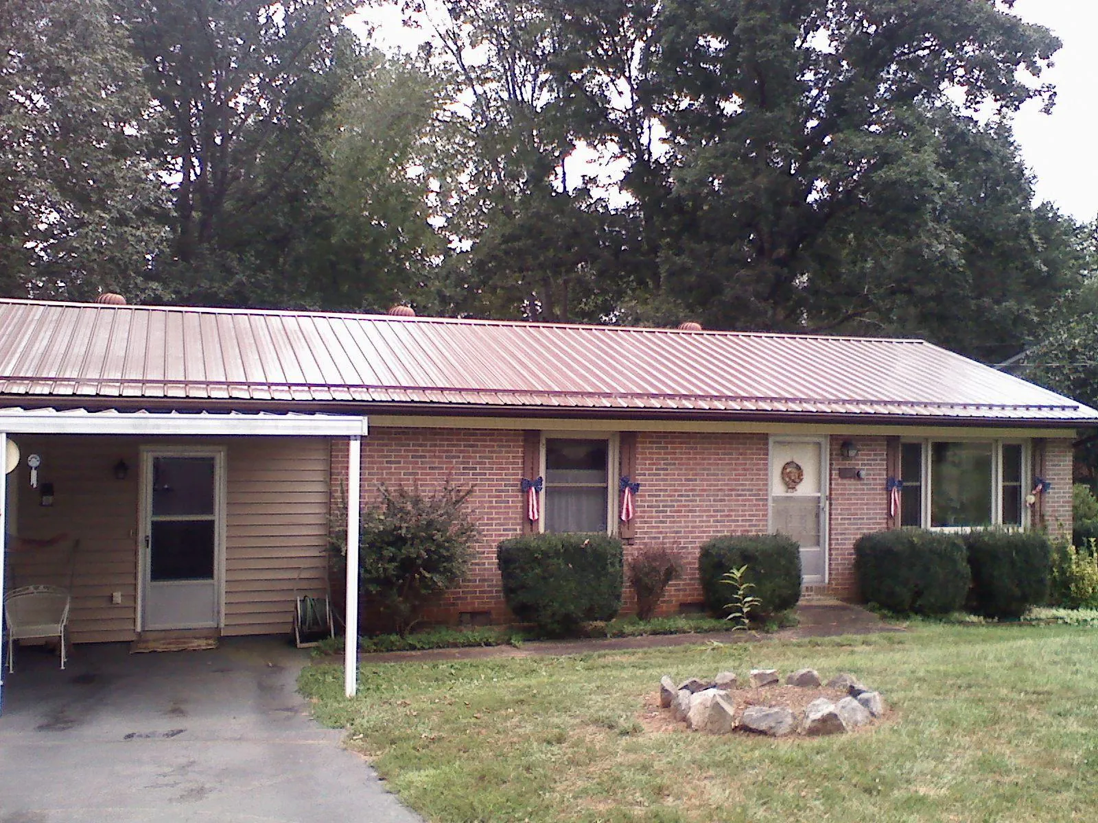 Bronze metal roof and carport on a brick ranch home — Roof Repair work by our crew in Lansing